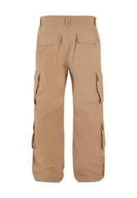 Tan cargo pants with multiple side and back pockets, elastic waistband, and a loose-fitting design. Made from durable fabric.
