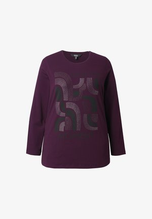 Fialové tričko s dlouhým rukávem se grafickým designem, který kombinuje tečkované a pevné vzory, zobrazující text "MILUJ MOMENT" v černé barvě.