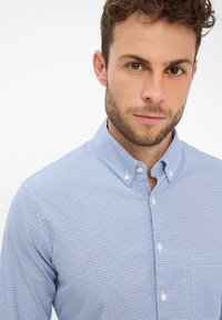 Hellblaues Hemd zum Knöpfen mit kleinem Kreis-Muster, ausgestattet mit klassischem Kragen und weißen Knöpfen, gefertigt aus glattem Baumwollstoff.