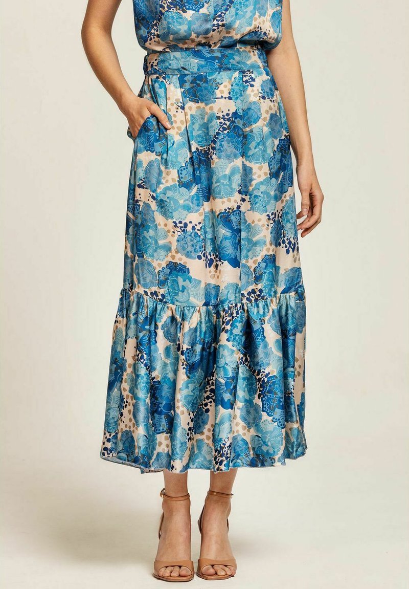 Blommig maxikjol i blå och beige nyanser, med lager av volanger i nederkant och sidofickor. Tillverkad av ett mjukt, lätt tyg.