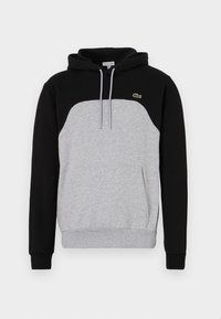Sudadera con capucha que tiene mangas negras y un cuerpo gris. Presenta un bolsillo tipo canguro y un pequeño logo verde en el pecho. Tela de mezcla de algodón.