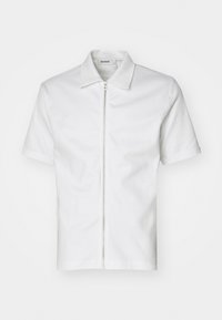 Chemise blanche à manches courtes avec une fermeture éclair frontale, un col structuré et une texture lisse. Design minimaliste sans motifs ni accents visibles.