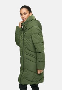 Abrigo acolchado verde con cuello alto, cierre de cremallera y bolsillos laterales. Tiene un patrón de acolchado y un corte holgado. Material cálido y superficie texturizada.