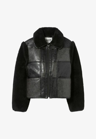 Chaqueta corta de cuero negro y borreguillo negro con cierre de cremallera, amplio cuello y detalles en panel rectangular en el cuerpo.