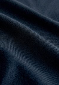 Tume ehk öösinine kangas, mille pind on sile ja tekstuuriga ning peene soonikuga, näidates õrnaid voltisid, mis viitavad kergele kootud materjalile.