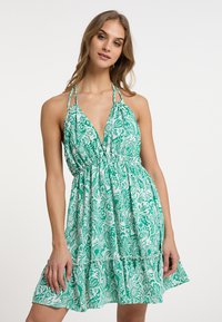 Rochie de soare cu model floral verde și alb, cu decolteu adânc în V, bretele halter și talie elastică, având un fustă evazată și un tiv ondulat.