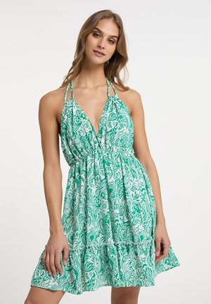 Sundress berbunga hijau dan putih dengan leher V yang dalam, tali halter, dan pinggang elastis, menampilkan rok melebar dan hem berkerut.