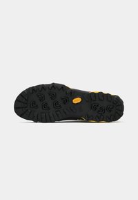 Čierna a žltá podrážka turistickej obuvi s hlbokými vzormi a logom Vibram na bielom pozadí.