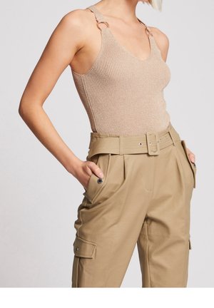 Beige ribbet tanktop med V-hals, metallic løkke detaljer på stropperne, parret med lyse khaki høj talje bukser med sidelommer.