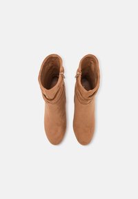 Ruske nubuk ankle čizme sa opuštenim dizajnom, zaobljenim vrhovima i bočnim rajsferšlusima. Tekstura deluje meko i glatko.