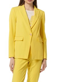 Veste jaune à coupe cintrée, fermeture à un bouton, revers crantés et deux poches avant. Texture lisse et forme structurée.