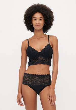 Mustat pitsiset bralette-hihnat ovat säädettävät ja niissä on aaltoilevat reunat, joita on yhdistetty sopivan korkean vyötärön pitsisiin alushousuihin, joissa on kukkakuviot.