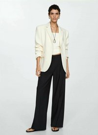 Bílý oversized blazer, krémový top, černé široké kalhoty a ploché sandály. Minimalistický design s hladkými texturami a jemnými šperkovými akcenty.