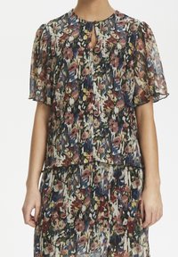 Blumenmuster Bluse aus semi-transparentem Stoff mit puffärmel, Schlüsselloch-Ausschnitt und mehrfarbigen Mustern in Rot-, Grün- und Blautönen.