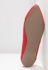 Červená texturová bota s špičatou špicí, perforovanými detaily po stranách a béžovou gumovou podrážkou. Značka viditelná na podrážce.