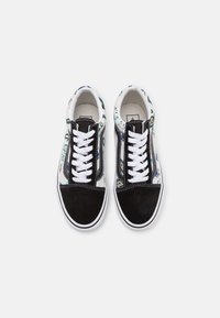 Baskets noires et blanches à lacets avec des motifs floraux sur les côtés, vues de dessus sur fond blanc.