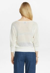 Weißer, mesh-strick Pullover mit lockerer Passform, weitem Ausschnitt und Ballonärmeln. Gerippte Bündchen und Saum. Klassisches Design mit strukturiertem Muster.