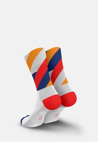 Colorful crew socks featuring a geometric pattern with orange, red, navy, and white stripes. Red cuffs and soles complement the design.