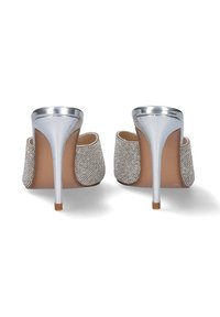 Mules plateados con tacón de metal, con una parte superior de tejido texturizado y una plantilla suave color beige. El tacón es alto y afilado.