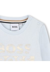 Γαλάζιο κοντομάνικο πουκάμισο με στρογγυλή λαιμόκοψη, διαθέτοντας μια υφή "BOSS" σε κρέμα και κουμπιά που διακοσμούν έναν ώμο.