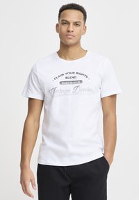 Hvit bomulls t-skjorte med trykt tekstdesign i svart og grått. Rund hals, korte ermer og en avslappet passform.