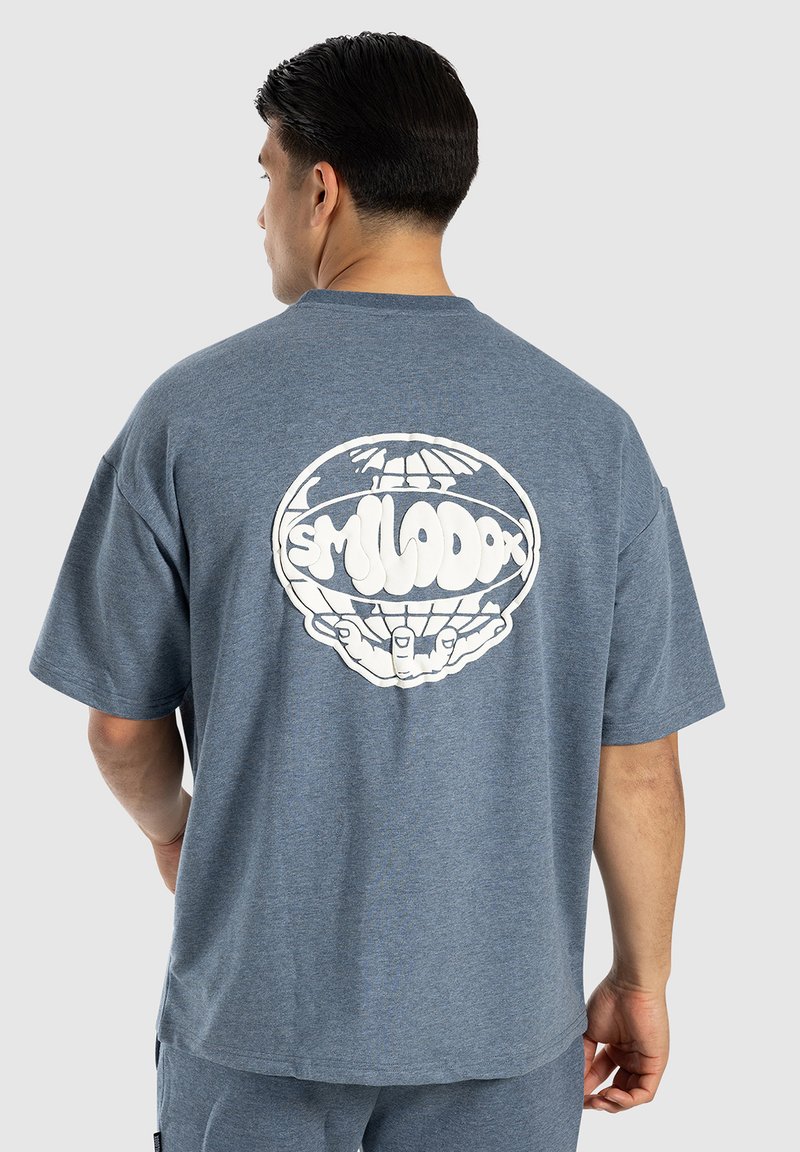 Blå kortærmet t-shirt med et stort hvidt grafik på ryggen, der viser en globe støttet af hænder. Blødt, tekstureret stof.