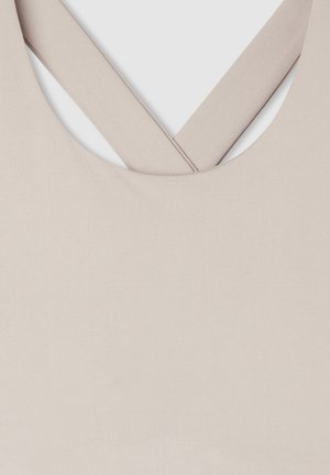 Reggiseno sportivo beige con una texture liscia, spalline larghe che formano una forma a X sul retro e un colletto arrotondato.