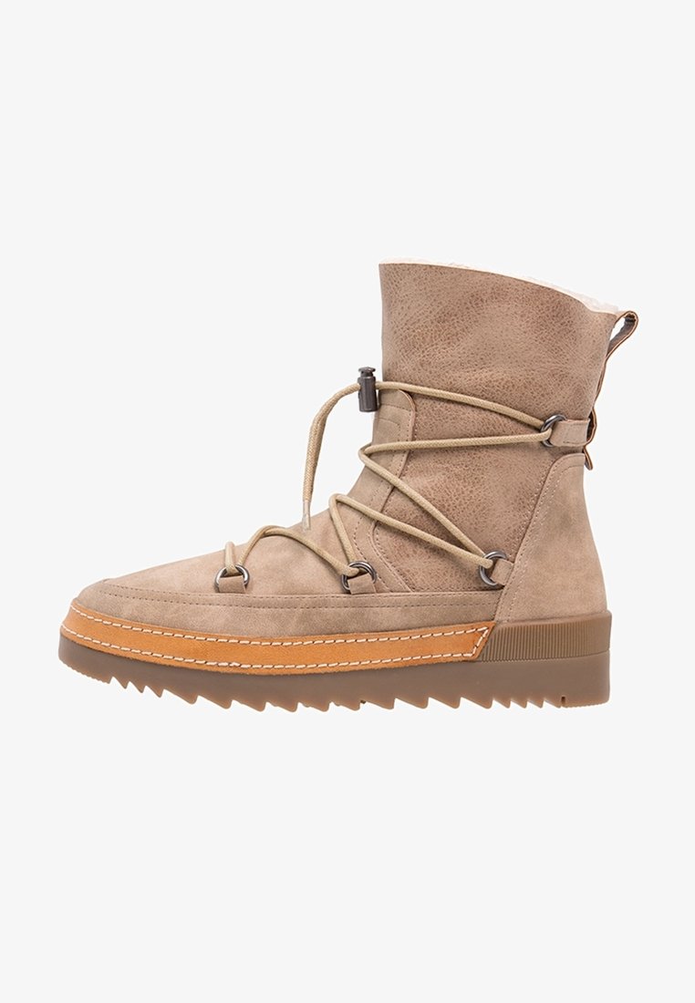 Bottine en daim beige clair avec doublure en fourrure d'agneau, lacets enveloppants, semelle en caoutchouc à crampons profonds, et bordure en cuir cousue contrastante.