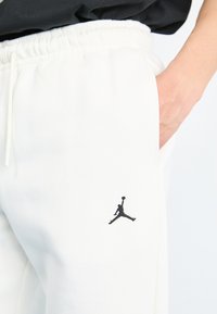 Witte sweatpants met een elastische tailleband, zijzakken en een zwart geborduurd Jumpman-logo op de linker dij.