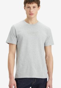 Camiseta de manga corta gris hecha de algodón, con un sutil logotipo bordado de Levi's en el pecho y un cuello redondo estándar.