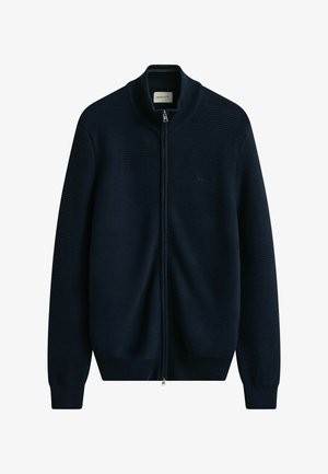 Mørkeblå, fuld lynlåssweater med ribbet tekstur, høj krave og subtilt logo på brystet.