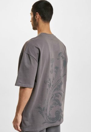 T-shirt grigia oversize in cotone, con maniche corte e un motivo decorativo scuro sul retro con la scritta "DAYS OF OLD."