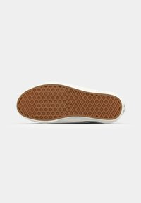Semelle de chaussure avec motif diamant et hexagone en caoutchouc marron avec bord blanc sur fond uni clair.