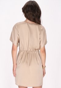 Rochie din satin bej cu mâneci scurte, talie strânsă și o textură netedă, fluidă, având un decolteu rotund și o fustă până la genunchi.