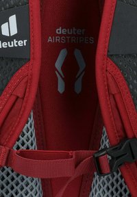 Lo zaino Deuter AIRSTRIPES presenta un interno con design in rete rossa e grigia, spallacci regolabili e una fibbia in plastica per un fissaggio sicuro.