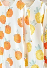 Två babybodys: en med orange mönster, den andra med gula ananastryck. Mjuk bomullstyg, rund hals, långa ärmar.