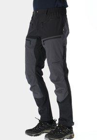 Ulkohousut mustana ja harmaana, valmistettu kestävästä kankaasta, jossa on useita vetoketjullisia taskuja ja vahvistetut polvialueet, suunniteltu aktiiviseen käyttöön.