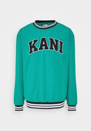 Suéter de manga larga color verde azulado con puños y cuello a rayas negras y blancas, con el llamativo texto negro "KANI" en el pecho.