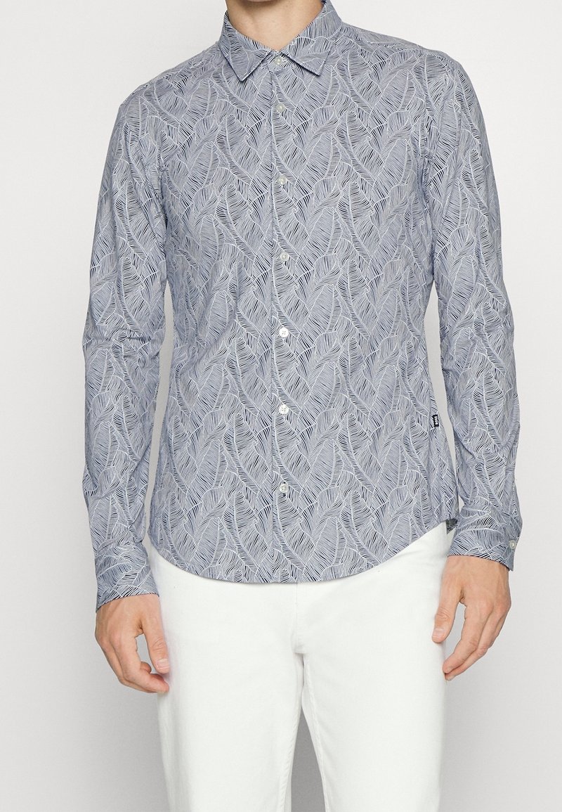 Niebieska koszula z długim rękawem z wzorem liści, z kołnierzykiem na guziki i zaokrąglonym dołem, wykonana z lekkiego materiału.