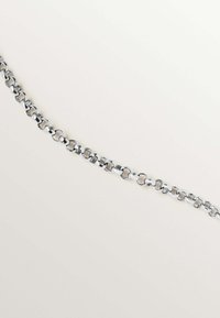 Pulsera de cadena de plata con eslabones redondeados entrelazados. Textura suave con un acabado brillante y un ancho uniforme en toda su longitud.