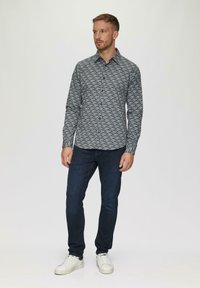 Blau gemustertes Langarmhemd mit Kragen, kombiniert mit dunklen Jeans und weißen Sneakern. Verfügt über eine Knopfleiste vorne und ein strukturiertes Material.