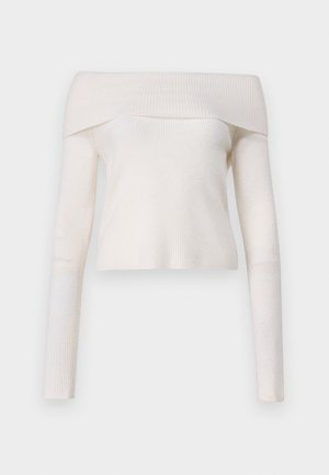 Avskåret ribbestrikket genser i kremfarge, med lange ermer og en tettsittende silhuett. Myk tekstur med en jevn overflate.