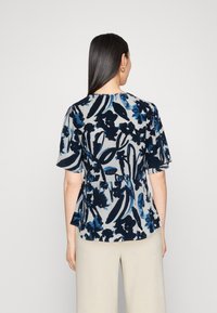 Blusa floral en tonos azul marino y azul claro, de mangas cortas, con cintura ceñida, tela fluida, estilo peplum y escote redondo.