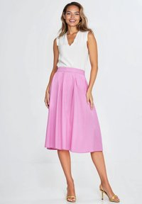 Różowa plisowana spódnica midi z dopasowanym paskiem, zestawiona z białą bezrękawnikową bluzką; gładka faktura tkaniny i błyszczące wykończenie.