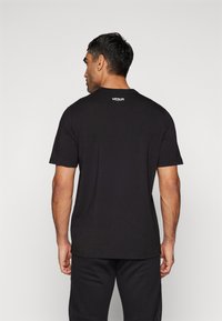 Sort bomulds t-shirt med korte ærmer og rund hals. Har et lille hvidt "Venum" logo på den øverste del af ryggen. Glat tekstur.