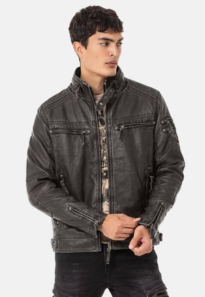 Schwarze Lederjacke mit einem Reißverschluss vorne, hohem Kragen, mehreren Reißverschlusstaschen und gepolsterten Akzenten an den Schultern. Glatte Textur und taillierte Passform.