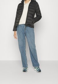 Czarna kurtka puchowa z kapturem, z poziomymi przeszyciami. W połączeniu z jasnoniebieskimi jeansami o wysokim stanie i wielokolorowymi trampkami.