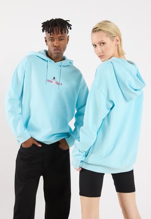 Light blue hoodie made of soft fabric, featuring a front pocket and adjustable drawstrings. Embroidered text "Never Again" on the chest.
