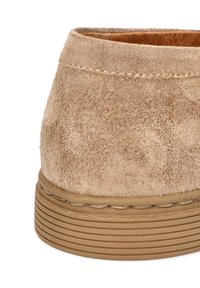 Beżowe zamszowe półbuty za kostkę o teksturowanej powierzchni, zaokrąglony obcas i żebrowana gumowa podeszwa. Widoczne przeszycia wzdłuż podstawy.