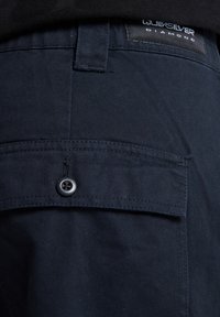 Donkerblauwe broek van textiel, met een achterzak voorzien van een zwarte knoop en een Quiksilver Diamond label dichtbij de tailleband.